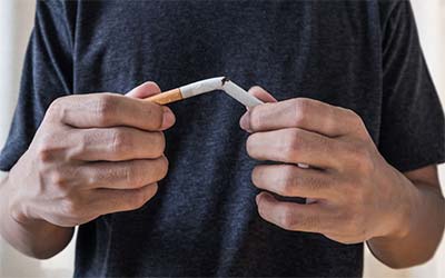 Person breaking a cigarette in half